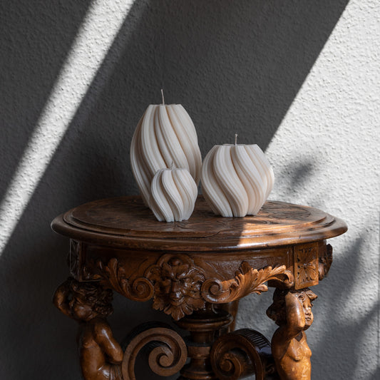 3er Kerzen Set Bøluna in natürlichem Cremeton – skulpturale Designkerzen, Rapswachs, handgefertigt in Hamburg, 100 % pflanzlich & nachhaltig. Studio Z. Stumpenkerzen in Wellenform, geschwungen und bauchig. Dekoriert auf barockem Tisch m Schattenspiel der Sonne.